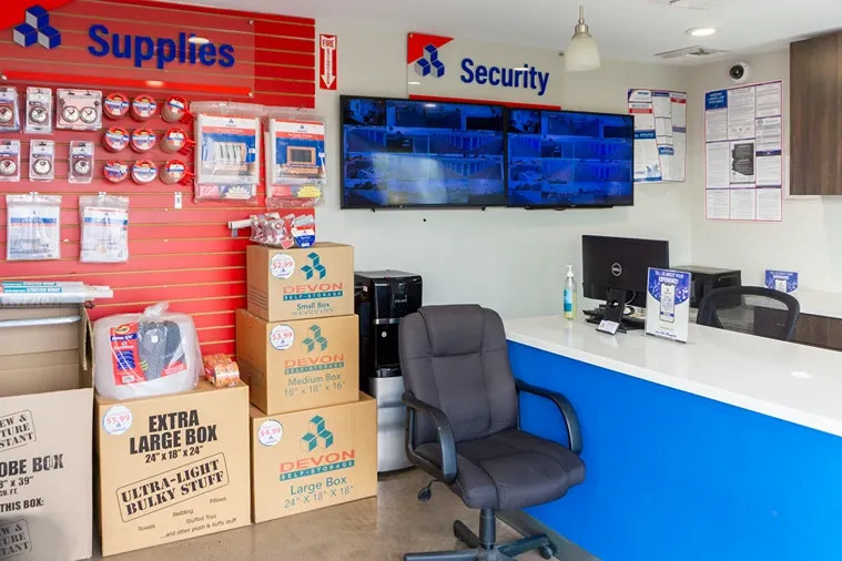 Storage office with moving supplies, customer service desk, and security monitoring screens
